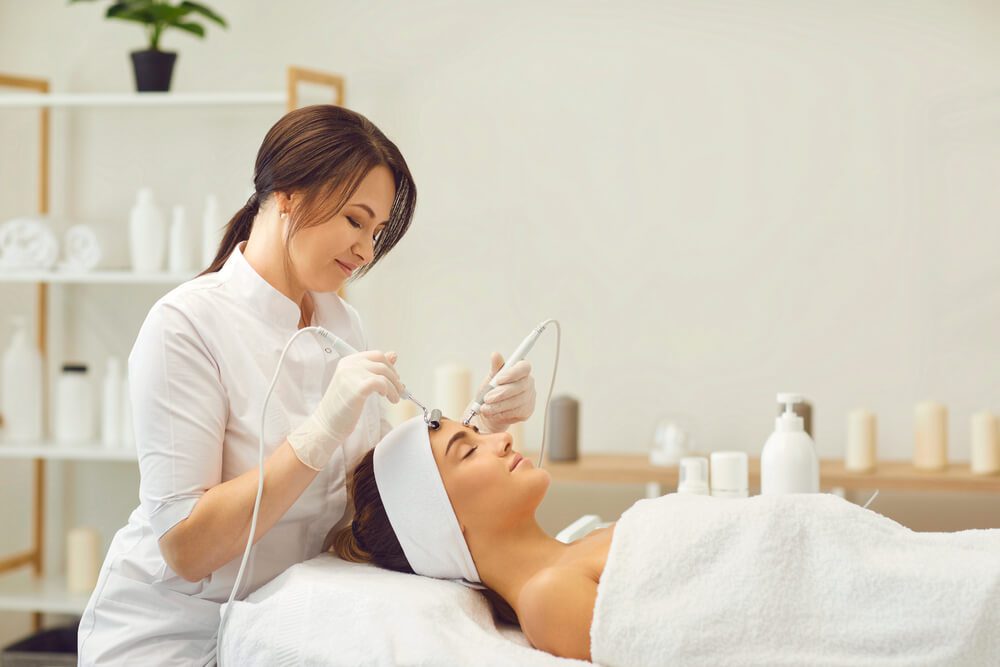 Beautician makes a young beautiful girl a vacuum facial treatment for rejuvenation.